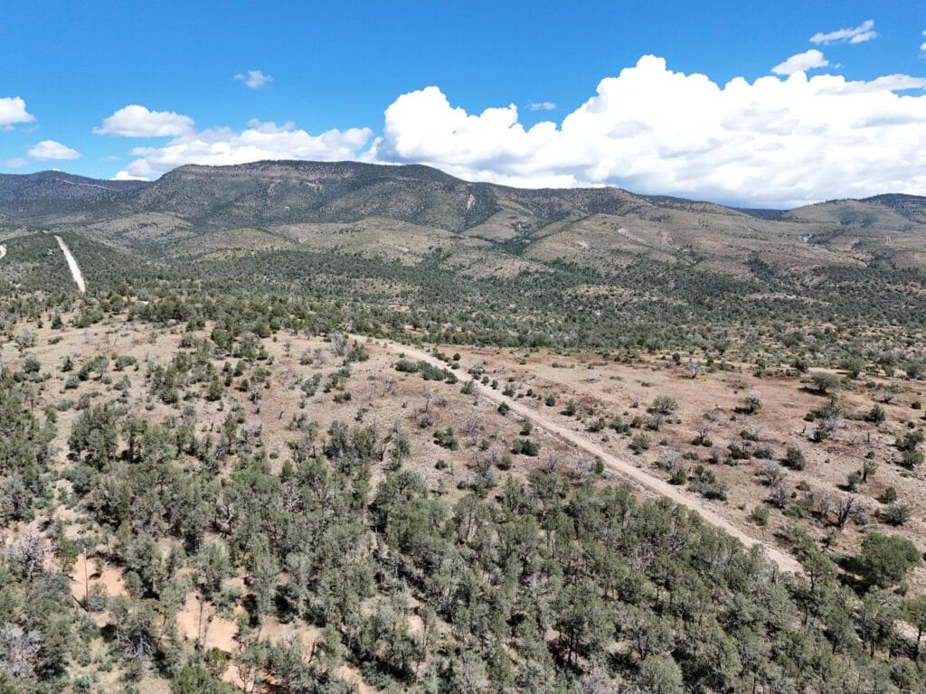 Aerial view looking toward the Sacramento Mountain range — dirt road through open scrubland surrounding the Timberon, NM lot (APN 11O4069113167045)