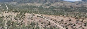 Aerial view looking toward the Sacramento Mountain range — dirt road through open scrubland surrounding the Timberon, NM lot (APN 11O4069113167045)