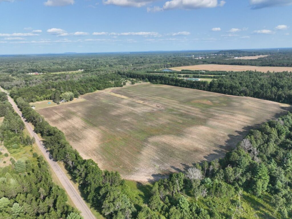 Mid-altitude aerial showing field with paved 18th Street West access road and distant lake, Necedah, WI (LOT 2)