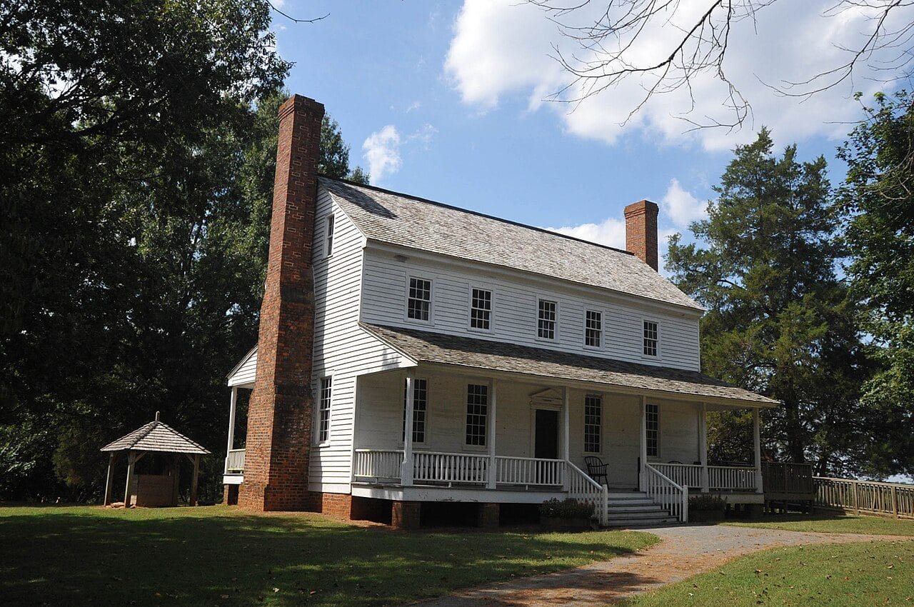 The white clapboard Alston House with its tall exterior brick chimney at House in the Horseshoe