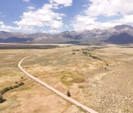 Aerial view showing Camino del Rey curving through the Baca Grande community with the Sangre de Cristo peaks filling the horizon, APN 460324300062
