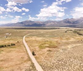 Drone view looking along Camino del Rey with the open San Luis Valley floor and the Sangre de Cristo range visible to the east, APN 460324300062