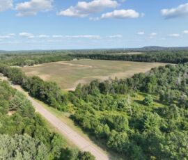 Mid-altitude aerial of paved road access with wooded pine surroundings and distant hills, Necedah, WI (LOT 2)