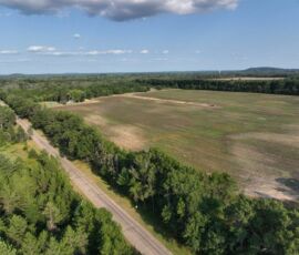 Mid-altitude aerial of field and 18th Street West with pines and distant hills, Necedah, WI (LOT 1)