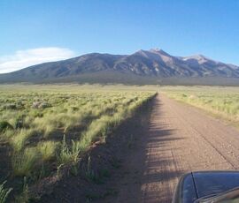 Area photo - dirt road heading toward Mt. Blanca across the San Luis Valley floor, representative of the terrain near Blanca, CO (APN 70303930)