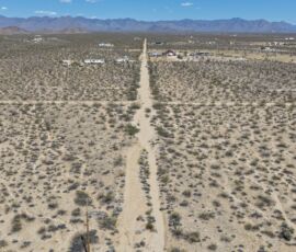 Aerial shot looking down the dirt road access with mountain range on the horizon, Yucca AZ