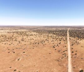 Drone overview of open desert terrain with dirt road along the boundary, Navajo County AZ — parcel 111-22-195